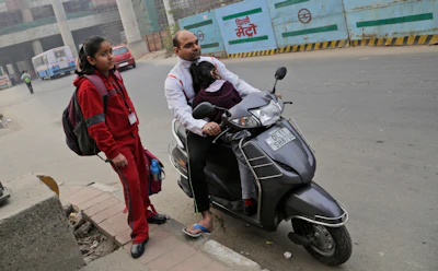 Ankur Jain, 35, a Delhi resident, and his daughters Aarna, 5, Navya, 10, wait for their school bus in New Delhi, India. Jain is worried that pollution will cut short the lives of everyone in his family. (AP Photo/Altaf Qadri)