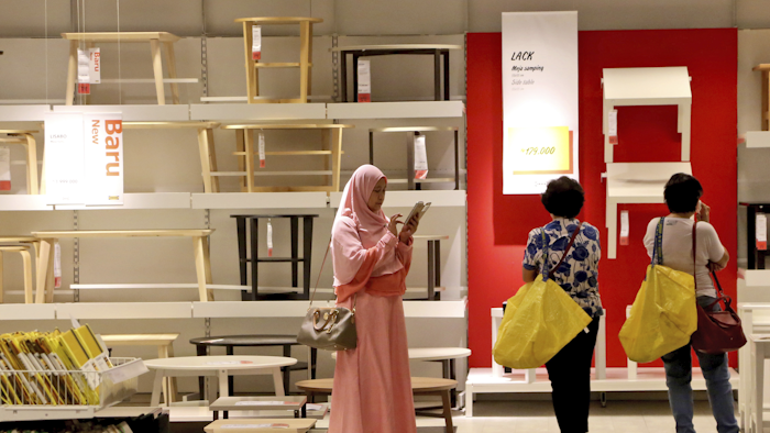A Muslim woman checks her mobile phone as two shoppers stand by at the IKEA store in Tangerang, Indonesia. (AP Photo/Tatan Syuflana)
