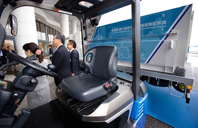 A Toyota fuel cell forklift, front, and a hydrogen fueling station and carrying hydrogen, background, are displayed in Yokohama, near Tokyo, after a press event for Hydrogen Supply Chain Demonstration Project Monday, March 14, 2016. Toyota Motor Corp. is trying to answer the main criticism of fuel cell cars: That making the hydrogen for the fuel is not clean. And so the Japanese automaker is going to make hydrogen from wind power. In a project, announced Monday, hydrogen from wind-power plant Hama Wing in Yokohama, southwest of Tokyo, will be compressed and transported by a truck to power fuel-cell forklifts at four sites in the port area - a factory, a vegetable-and-fruit market and two warehouses. (AP Photo/Shizuo Kambayashi)