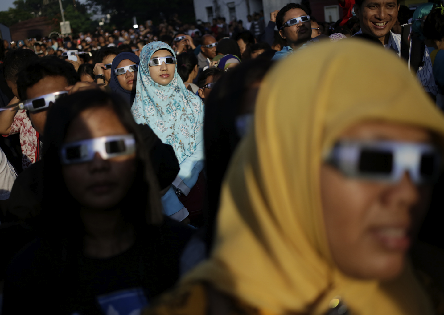 People look up at the sun wearing protective glasses to watch a solar eclipse in Jakarta, Indonesia. (AP Photo/Dita Alangkara)