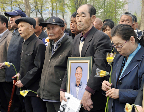 Chinese forced laborers, second and third from left, and bereaved families stand during a memorial gathering before suing a file against Mitsubishi Materials Corp. in front of High People's Court in Shijiazhuang, China's Hebei Province. (Kyodo News via AP)