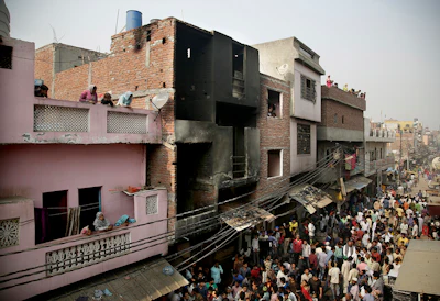 Locals crowd outside a residential building used as a garment factory, which was gutted in a fire in the outskirts of New Delhi, India, Friday, Nov. 11, 2016. The fire, that broke out the garment factory basement, trapped and killed more than a dozen workers as they slept in the building. (AP Photo/Altaf Qadri)