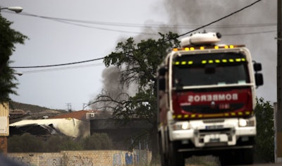 A firefighter truck leaves as smoke rises from a factory in Arganda del Rey (AP photo)