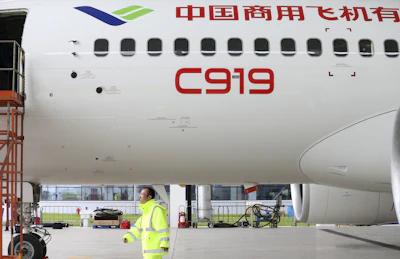 In this Thursday, May 4, 2017 photo, a worker walks past a COMAC C919 aircraft in an airplane hangar in Shanghai. China’s first large homemade passenger jetliner is due to make its maiden flight from Shanghai later Friday. (Chinatopix via AP)