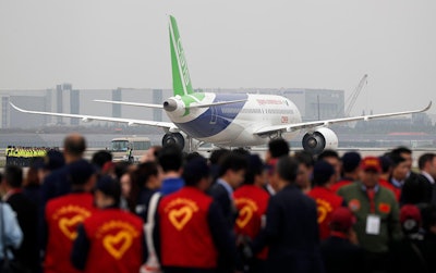 Attendees gather as a Chinese C919 passenger jet sits on the tarmac before its scheduled first flight at Pudong International Airport in Shanghai, Friday, May 5, 2017. China is touting the C919 as a rival to single-aisle jets the Airbus A320 and Boeing 737. The plane was originally due to fly in 2014 before being delivered to buyers in 2016, but has been beset by delays blamed on manufacturing problems. (AP Photo/Andy Wong, Pool)