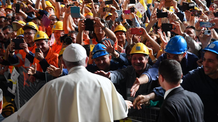 Pope Francis is cheered by workers at the ILVA steel-making company in Genoa, Italy, Saturday, May 27, 2017. Pope Francis has begun a one-day visit to the northern Italian port city of Genoa to meet with workers, poor and homeless people, refugees and prisoners. His opened his visit at ILVA, a troubled steel-making company, where workers in hard hats awaited him. The visit puts a focus on the plight of workers whose lives have been made precarious by years of economic crisis. (Luca Zennaro/ANSA via AP)