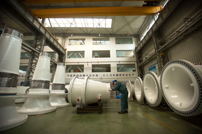 In this Nov. 9, 2015 photo, a worker inspects wind turbine parts at a Goldwind wind turbine factory in Beijing. Increasing amounts of green energy have gone unused in China as it struggles to integrate wind and solar power into a dated electricity network dominated by coal. (AP Photo/Mark Schiefelbein)