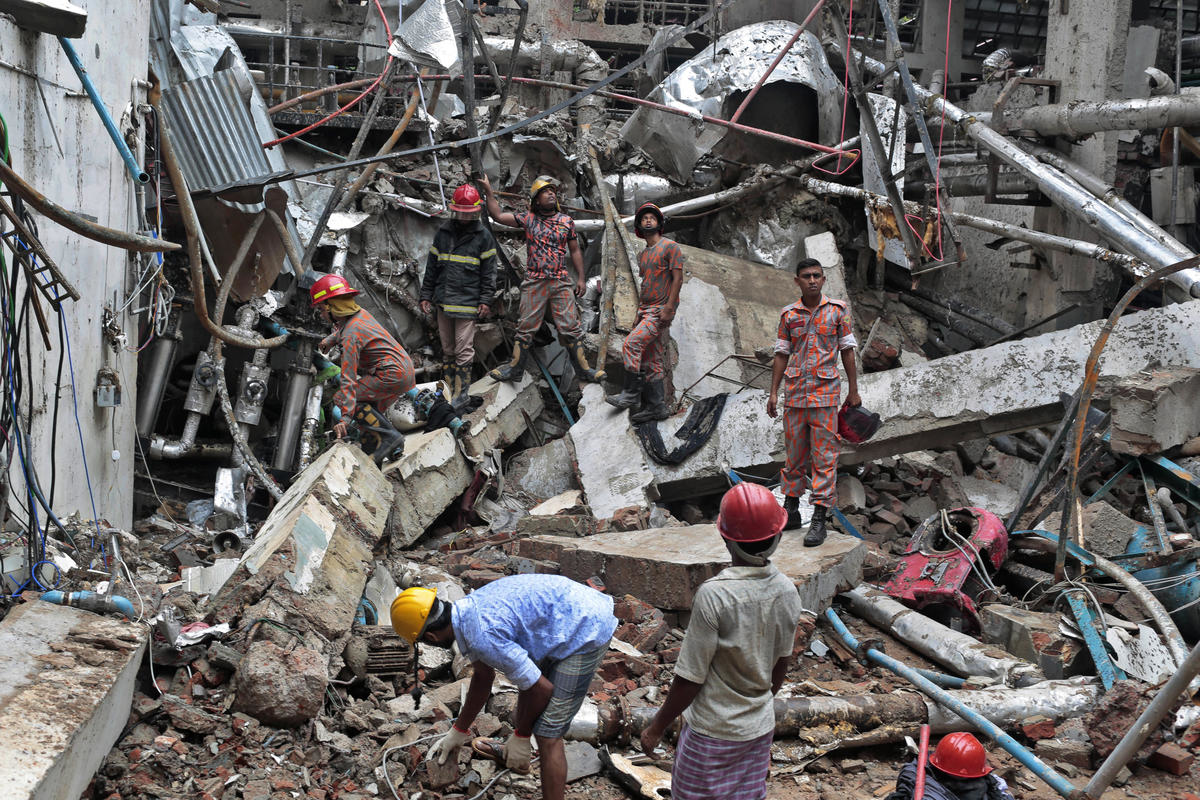 Bangladeshi firefighters and rescuers stand on the debris after a Monday evening boiler explosion at a garment factory owned by export-oriented Multifabs Ltd. at Kashimpur area in Gazipur district, outside capital Dhaka, Bangladesh, Tuesday, July 4, 2017. (AP Photo/A.M. Ahad)