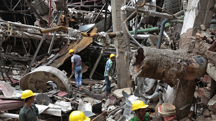 Bangladeshi rescuers stand on the debris after a Monday evening boiler explosion at a garment factory owned by export-oriented Multifabs Ltd. at Kashimpur area in Gazipur district, outside capital Dhaka, Bangladesh, Tuesday, July 4, 2017. (AP Photo/A.M. Ahad)