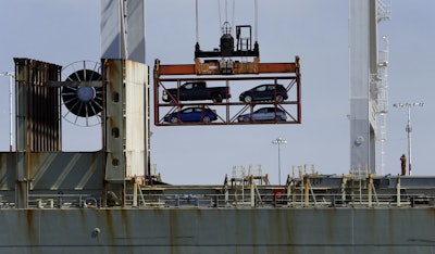 In this July 13, 2017 file photo, a crane transporting vehicles operates on a container ship at the Port of Oakland, in Oakland, Calif. A key draw for foreign assembly plants and investment has been Mexico's low wages. With many workers unable to afford the vehicles Mexico produces, the country exports about three times as many cars as are purchased domestically, most to the United States. (AP Photo/Ben Margot, File)