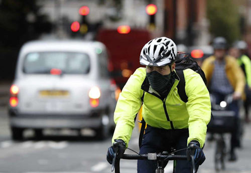 A cyclist wears a mask in central London, Monday, Oct. 23, 2017. The Mayor of London Sadiq Khan officially launched T-Charge on Monday. The T-Charge will be the toughest vehicle emissions standard of any world city, affecting the oldest and most polluting vehicles. (AP Photo/Kirsty Wigglesworth)