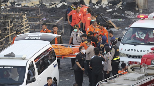 Police officers and rescuers carry a body at the site of an explosion at a firecracker factory in Tangerang, on the outskirts of Jakarta, Indonesia, Thursday, Oct. 26, 2017. The explosion and raging fire killed a number of people and injured dozens, police said. (AP Photo/Tatan Syuflana)