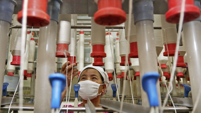 A worker checks the cotton thread barrels in a textile factory in Huaibei in central China's Anhui province. Chinese manufacturing activity expanded in October at a slower pace than the previous month as output weakened on softer demand in the world’s No. 2 economy, an official survey said Tuesday, Oct. 31. (Chinatopix via AP)
