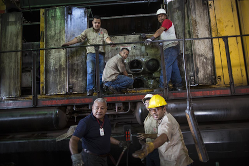 In this Nov. 1, 2017 photo, workers repair a locomotive at Ferrominera Orinoco, in Ciudad Guayana, Bolivar state, Venezuela. In cash-strapped Venezuela, there's no money to buy spare parts. (AP Photo/Rodrigo Abd)