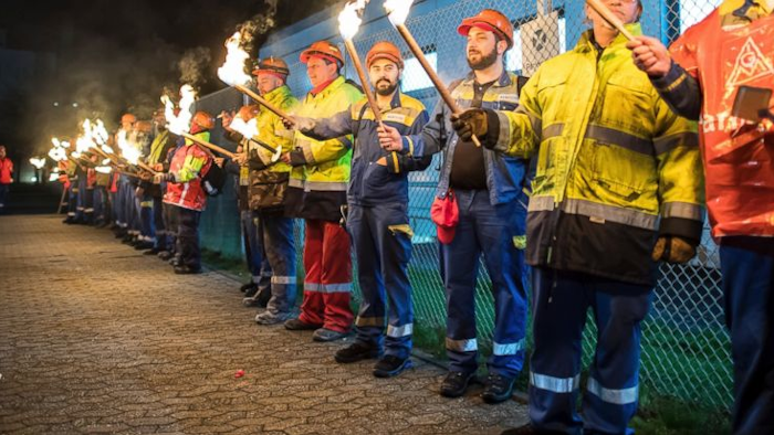 The night shift workers meet for a warning strike assembly of the IG Metall (Industrial Union of Metalworkers) in front of the gates of the Aluminium Norf GmbH in Neuss, Germany, Tuesday, Jan. 9, 2018. Germany’s largest industrial union pressed its demands for pay rises and the possibility for reduced work hours for its 3.9 million members with renewed short-term strikes Tuesday, saying the economy’s steady growth justifies better compensation and conditions. (Guido Kirchner/dpa via AP)