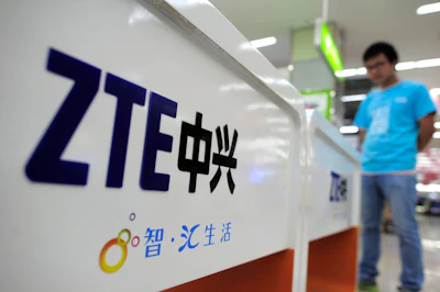 In this Oct. 8, 2012, file photo, a salesperson stands at counters selling mobile phones produced by ZTE Corp. at an appliance store in Wuhan in central China's Hubei province. Image credit: Chinatopix Via AP, File