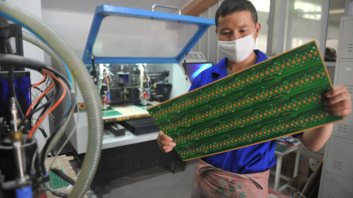In this May 22, 2018 photo, a staff member works in a circuit board manufacturing facility in Hangzhou in eastern China's Zhejiang province. Image credit: Chinatopix via AP
