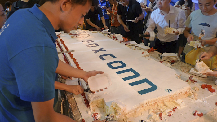 Workers cut a giant cake to celebrate Taiwan-based contract manufacturing giant Foxconn's 30th anniversary of its first investment in Shenzhen, south China's Guangdong province Wednesday, June 6, 2018. Image credit: AP Photo/Kelvin Chan