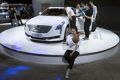 A woman poses for a photo in front of a CT6 Cadillac during the Consumer Electronics Show Asia 2018 in Shanghai, China on Friday, June 15, 2018. Image credit: AP Photo/Sam McNeil