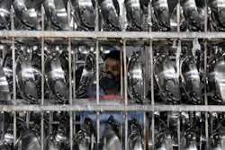In this Monday, June 25, 2018, photo, a man inspects cooking woks in a factory in Hangzhou in east China's Zhejiang province. Image credit: Chinatopix via AP