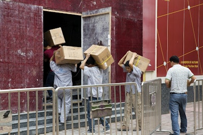 Workers carry boxes of LED lights into a renovation site in Beijing, China, Tuesday, July 3, 2018. Image credit: AP Photo/Ng Han Guan