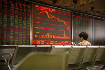 A Chinese investor uses her smartphone as she monitors stock prices at a brokerage house in Beijing, Friday, July 6, 2018. Image credit: AP Photo/Mark Schiefelbein