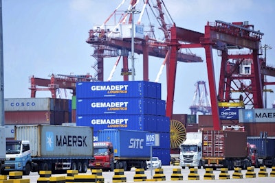 Trucks haul containers from a container port in Qingdao in eastern China's Shandong province Friday, July 6, 2018. Image credit: Chinatopix via AP