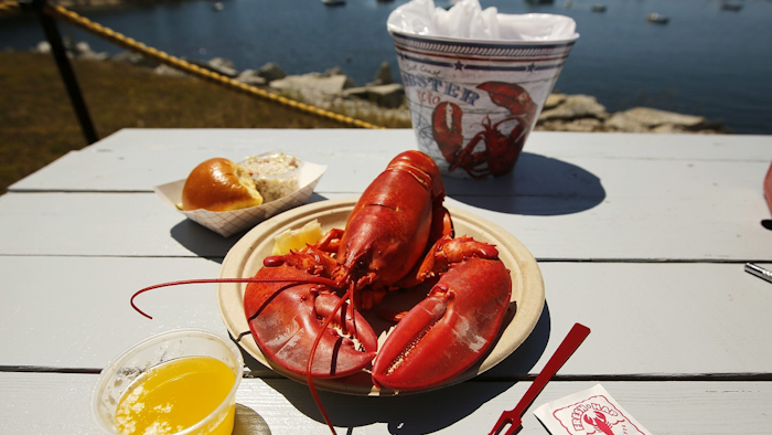 In this Thursday, July 19, 2018 photo, a cooked lobster is served on a picnic table at McLoon's Lobster Shack in Spruce Head, Maine. Image credit: AP Photo/Robert F. Bukaty