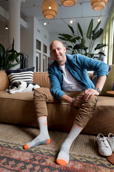 In this June 22, 2018, photo, David Health, CEO and co-founder of Bombas, poses for a photo during an interview in his New York office. Heath and his partner Randy Goldberg spent two years developing socks with features like blister tabs and arch support. Then they teamed up with shelters and nonprofit groups, and the company donates a pair for every pair it sells. (AP Photo/Mark Lennihan)