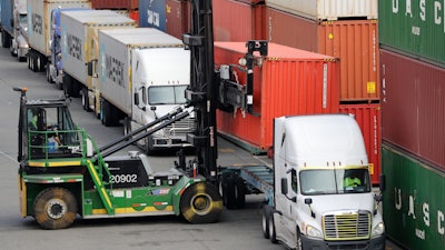 In this Oct. 2, 2019 file photo, a shipping container is lifted off the back of a truck as others wait in line to have their cargo unloaded at a terminal on Harbor Island in Seattle.