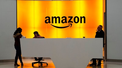 In this Feb. 14, 2019, file photo people stand in the lobby for Amazon offices in New York. Amazon says President Donald Trump's “improper pressure' and behind-the-scenes attacks harmed its chances of winning a $10 billion Pentagon contract. Amazon argues in a lawsuit unsealed Monday, Dec. 9, that the decision should be revisited because of “substantial and pervasive errors' and Trump's interference.
