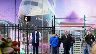 Boeing workers exit the plant in front of a giant mural of a jet on the side of the manufacturing building behind Monday, Dec. 16, 2019, in Renton, Wash. Shares of Boeing fell before the opening bell on a report that the company may cut production of its troubled 737 MAX or even end production all together.