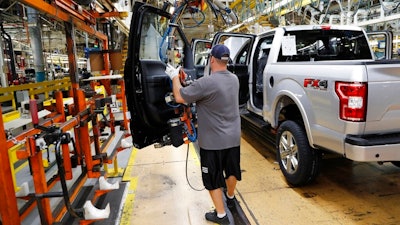 In this Sept. 27, 2018, file photo a United Auto Workers assemblyman installs the front doors on a 2018 Ford F-150 truck being assembled at the Ford Rouge assembly plant in Dearborn, Mich. Ford Motor Co. said Tuesday, Dec. 17, 2019, that it is adding 3,000 jobs at two factories in the Detroit area and investing $1.45 billion to build new pickup trucks, SUVs, and electric and autonomous vehicles. At the Dearborn truck plant $700 million will be invested.