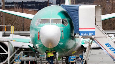 A worker looks up underneath a Boeing 737 MAX jet Monday, Dec. 16, 2019, in Renton, Wash. Shares of Boeing fell before the opening bell on a report that the company may cut production of its troubled 737 MAX or even end production all together.