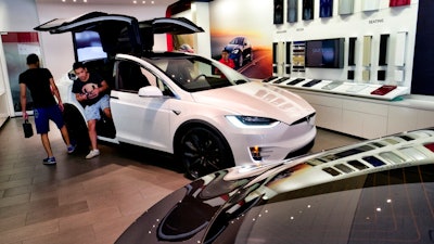 In this Aug. 8, 2018, file photo, customers check out the Tesla X, at the Tesla showroom in Santa Monica, Calif. California's rebate program to entice more drivers to purchase electric vehicles got less generous, especially for those looking to buy luxury models. Effective Tuesday, Dec. 3, 2019, regulators stopped offering rebates for electric cars or plug-in hybrids that cost more than $60,000.