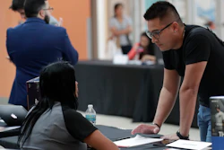 In this Oct. 1, 2019 file photo, Gabriel Picon, right, talks with a representative from GameStop during a job fair at Dolphin Mall in Miami.