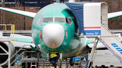 In this Dec. 16, 2019, file photo, a worker looks up underneath a Boeing 737 MAX jet, in Renton, Wash. Boeing has found a new software problem on its grounded 737 Max jetliner. The aircraft maker said, Friday, Jan. 17, 2020, it is making the necessary changes and working with the Federal Aviation Administration.