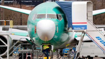 In this Dec. 16, 2019, file photo a worker looks up underneath a Boeing 737 MAX jet in Renton, Wash. Boeing doesn't expect federal regulators to approve its changes to the grounded 737 Max until this summer, according to two people familiar with the matter.