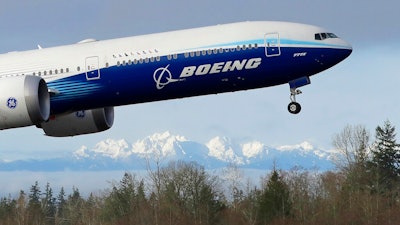 In this Jan. 25, 2020, file photo a Boeing 777X airplane takes off on its first flight with the Olympic Mountains in the background at Paine Field in Everett, Wash. Boeing Co. reports financial results on Wednesday, Jan. 29.