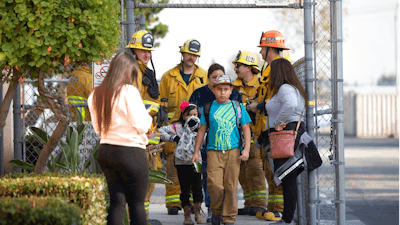 Children evacuate the Park Avenue Elementary school in Cudahy, Calif., Tuesday, Jan. 14, 2020 after an aircraft dumped fuel that fell onto the elementary school playground. Tuesday, Jan. 14, 2020. A jet returning to LAX dumped its fuel over the neighborhood and the school. Affected people at the school were treated for skin and eye irritation. No patients were transported to hospitals.