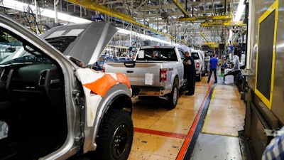 In this Sept. 27, 2018, file photo a United Auto Workers assemblyman works on a 2018 Ford F-150 truck being assembled at the Ford Rouge assembly plant in Dearborn, Mich. Ford is recalling its popular F-150 pickup truck in Canada to fix a problem with electric tailgate latches, but identical trucks aren't being recalled in the U.S.