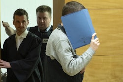 A 57-year old defendant hides his face at the courtroom in Bielefeld, Germany, Thursday, March 7, 2019. A judge in Germany has found the man guilty of poisoning his co-workers' sandwiches with mercury, lead acetate and other chemicals over several years and sentenced him to life in prison.