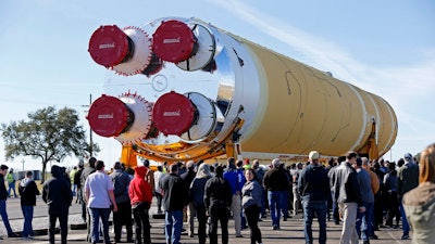 Employees and contractors watch as the core stage of NASA's Space Launch System rocket, that will be used for the Artemis 1 Mission, is moved to the Pegasus barge, at the NASA Michoud Assembly Facility where it was built, in New Orleans, Wednesday, Jan. 8, 2020. It will be transported to NASA's Stennis Space Center in Mississippi for its green run test.