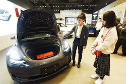 In this Nov. 24, 2019, photo, a saleswoman talks about a Tesla Model 3 car at a Tesla showroom in Hangzhou in eastern China's Zhejiang Province. Tesla's Shanghai factory delivered its first cars to customers Monday, Jan. 6, 2020, and chief executive Elon Musk said the electric automaker plans to set up a design center in China to create a model for worldwide sales.