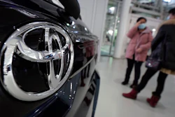 Visitors stand by a Toyota car displayed at its showroom Thursday, Jan. 30, 2020, in Tokyo. German automaker Volkswagen has kept its lead as the world's largest automaker as Japanese rival Toyota sold fewer vehicles last year. Toyota Motor Corp. said Thursday it sold 10.74 million vehicles around the world in 2019, trailing Volkswagen at 10.97 million vehicles.