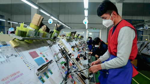 In this Feb. 13 photo, masked workers assembly wiring for automobile at a factory in Qingdao in east China's Shandong province. Automakers are gradually reopening factories in China that were idled by anti-virus controls as they try to reverse a sales slump in their biggest market.