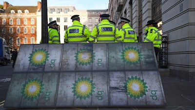 Police officers stand near activists outside BP's headquarters to mark the first day of the oil company's new chief executive Bernard Looney, at St James' Square in London, Wednesday Feb. 5, 2020.