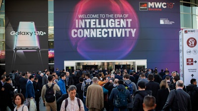 In this Feb. 25, 2019 photo, attendees walk to enter at the Mobile World Congress wireless show in Barcelona, Spain. Organizers of the world’s biggest mobile technology fair are pulling the plug over worries about the viral outbreak from China. The annual Mobile World Congress show will no longer be held as planned in Barcelona, Spain, on Feb. 24-27.