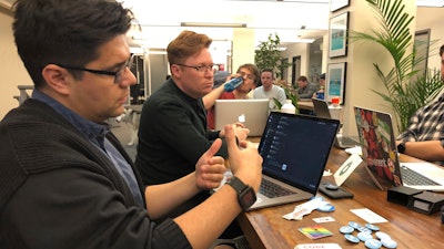 In this Monday, Jan. 13, 2020, photograph taken in Denver, software engineer David Viramontes, front, and digital strategist Patrick Collins direct a meeting of Code For Denver.