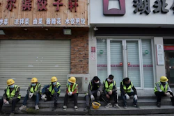 Workers take a rest near the closed restaurant and bank in Wuhan in central China's Hubei province.